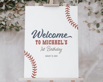 May include: White welcome sign with red and blue baseball stitching design. The sign reads "Welcome to Michael's 1st Birthday August 15, 2024".