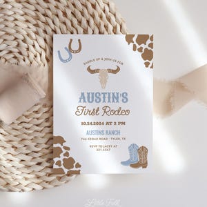May include: A light blue and brown invitation with a cowboy boot design. The invitation reads "Saddle Up & Join Us For Austin's First Rodeo" with the date and time "10.24.2024 at 2 PM" and the location "Austin's Ranch 746 Cedar Road Tyler, TX". The invitation also includes the RSVP information "RSVP to Jacey at 321.4567".