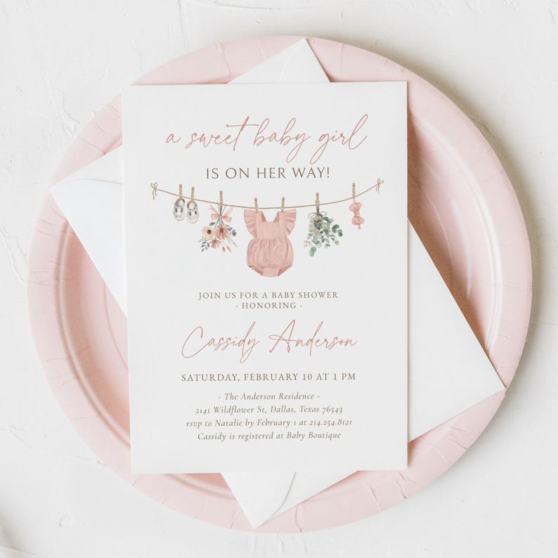 May include: A pink baby shower invitation with a clothesline illustration featuring a pink onesie, shoes, flowers, and a bow. The text reads "a sweet baby girl is on her way!" and includes the name "Cassidy Anderson" and details for the event.