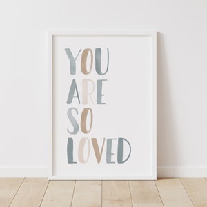Puede incluir: Una impresi&oacute;n enmarcada en blanco con el texto "YOU ARE SO LOVED" en letras de acuarela azul y beige.