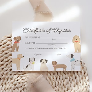 May include: A white certificate with the text "Certificate of Adoption" in elegant script. The certificate features illustrations of various dog breeds and includes spaces to fill in the pet's and owner's names, along with a signature and date.