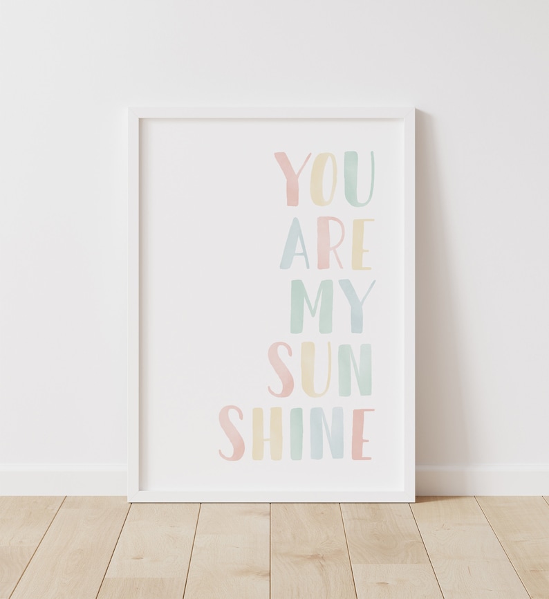 May include: A white framed print with the text "You are my sunshine" in pastel colors. The text is arranged vertically with each word in a different color.