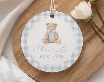 May include: Round gift tag with a light blue gingham border and a central image of a teddy bear wearing a blue bow. The tag reads "Thank You BEARY MUCH" in elegant script, attached with a natural twine.
