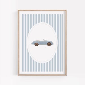 Pu&ograve; includere: Stampa incorniciata con un'illustrazione di un'auto cabriolet azzurra. L'auto &egrave; centrata all'interno di una forma ovale, su uno sfondo di strisce verticali blu e bianche. La cornice &egrave; in legno chiaro.