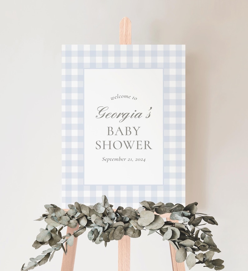 K&ouml;nnte beinhalten: Ein blaues und wei&szlig;es Gingham-Willkommenszeichen f&uuml;r eine Babyparty. Das Schild lautet "Willkommen zur Babyparty von Georgia, 21. September 2024".