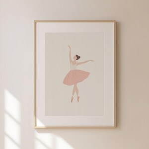 May include: A framed print featuring a minimalist illustration of a ballerina. The dancer is depicted in a graceful pose, wearing a pink tutu and pointe shoes. The artwork has a soft, neutral color palette, with a light background and a wooden frame.
