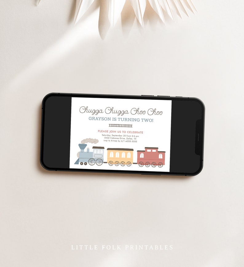 May include: A smartphone displays a birthday invitation with a train illustration. The text reads "Chugga Chugga Choo Choo, Grayson is turning two!" The invitation includes details about the party date, time, and location.