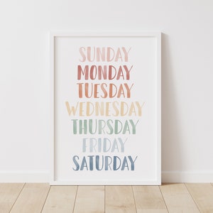 Puede incluir: Una impresi&oacute;n enmarcada en blanco con los d&iacute;as de la semana escritos en una fuente de acuarela colorida. Los colores pasan del rosa al azul.