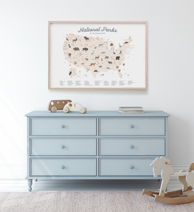 Puede incluir: Una c&oacute;moda azul claro con seis cajones y pomos de madera. La c&oacute;moda est&aacute; en una habitaci&oacute;n con una pared blanca y una alfombra en el suelo. Un mapa enmarcado de los Estados Unidos con el texto "National Parks of the United States" est&aacute; colgado en la pared sobre la c&oacute;moda. Un autob&uacute;s de juguete de madera y un coche est&aacute;n encima de la c&oacute;moda. Un caballo de balanc&iacute;n de madera est&aacute; en la alfombra delante de la c&oacute;moda.