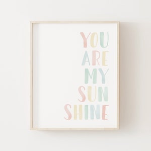 May include: A framed print with the text "You are my sunshine" in a rainbow of pastel colors. The words are arranged vertically, with each word in a different color.