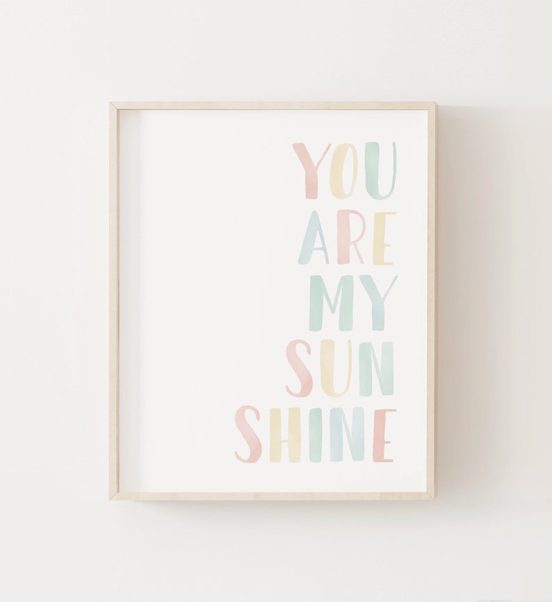 May include: A framed print with the text "You are my sunshine" in a rainbow of pastel colors. The words are arranged vertically, with each word in a different color.
