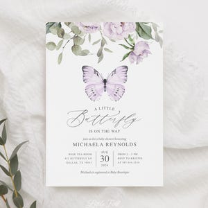 May include: A baby shower invitation with a watercolor illustration of a purple butterfly and flowers. The text reads "A Little Butterfly is on the Way" and includes the name Michaela Reynolds, the date August 30, 2024, and the location Rose Tea Room, 432 Butterfly Ln, Dallas, TX 76543.