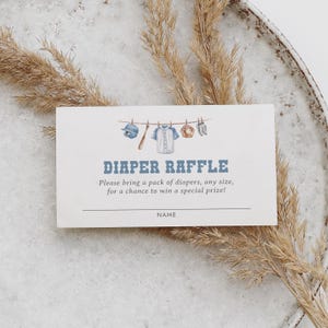 May include: A light blue and white diaper raffle card with baseball illustrations. The card says "DIAPER RAFFLE" in blue text, with instructions to bring diapers for a prize. A baseball bat, glove, and jersey are depicted on a clothesline.
