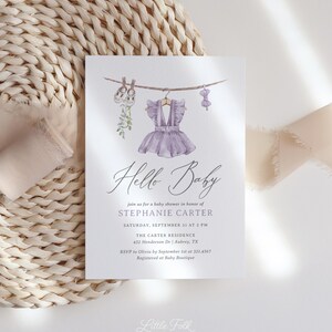 May include: A baby shower invitation with a watercolor design. The invitation features a purple dress, baby shoes, and a bow hanging on a clothesline. The text reads "Hello Baby" and includes event details.