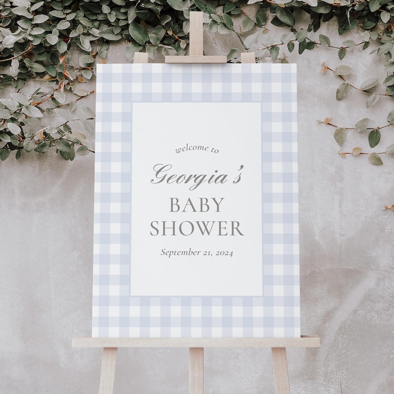 K&ouml;nnte beinhalten: Ein blaues und wei&szlig;es Gingham-Willkommenszeichen f&uuml;r eine Babyparty. Das Schild lautet "Willkommen zu Georgias Babyparty, 21. September 2024".