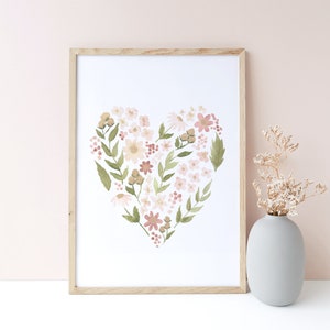 May include: A framed print of a watercolor painting of a heart shape made of pink, white, and green flowers. The print is on a white background and is framed in a light wood frame.