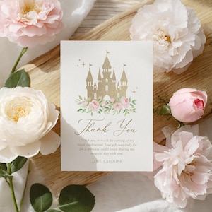 Peut inclure: Une carte blanche avec une illustration de château doré, des fleurs roses et l'inscription "Thank You". La carte contient également le texte "Thank you so much for coming to my royal celebration!" et "LOVE, CAROLINE."