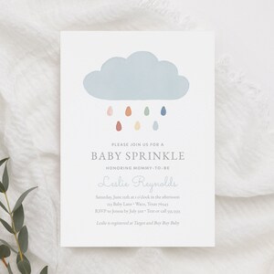 May include: A baby sprinkle invitation featuring a blue cloud and colourful raindrops. The invitation reads "Please join us for a baby sprinkle honouring mommy-to-be Leslie Reynolds". The date, time, location, RSVP details, and registry information are also provided.
