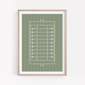 Puede incluir: Una impresión enmarcada que presenta un diseño estilizado de un campo de fútbol americano. El campo está representado con líneas blancas sobre un fondo verde apagado, con marcadores de yardas y postes de portería. La impresión está enmarcada en madera clara.