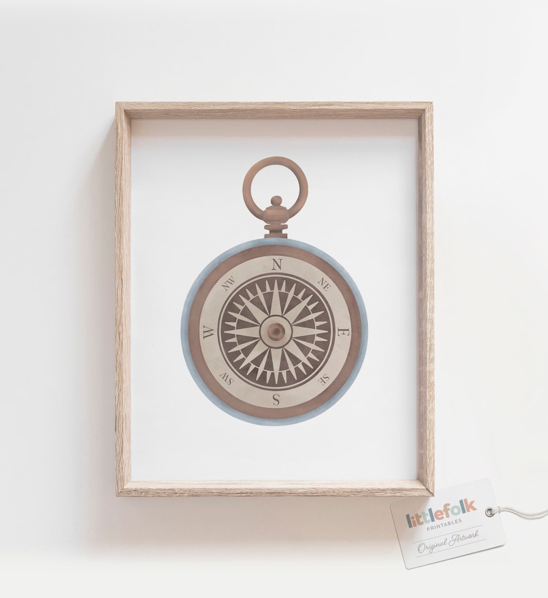 Peut inclure: Une boussole de style vintage avec un cadran bleu et des marquages ​​marrons. La boussole est encadr&eacute;e dans un cadre en bois clair et porte une petite &eacute;tiquette avec le texte "littlefolk printables Original Artwork".