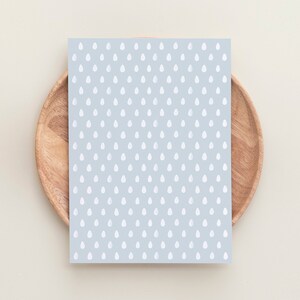 May include: A light blue card with a white raindrop pattern. The card is on a wooden plate.