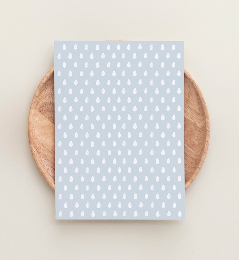 May include: A light blue card with a white raindrop pattern. The card is on a wooden plate.