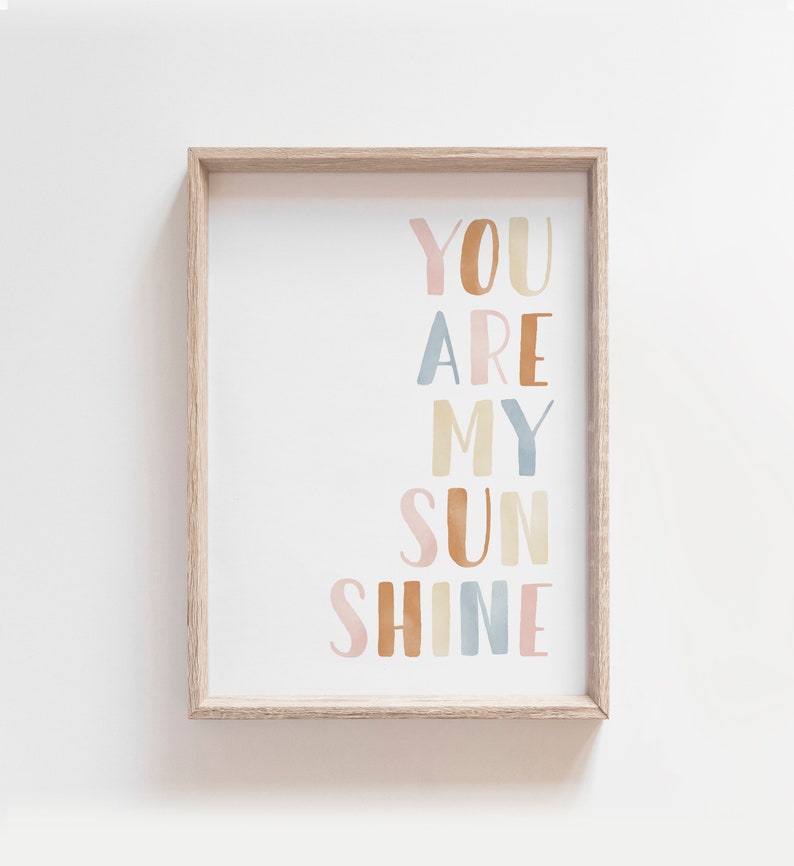 May include: A framed print with the text "You are my sunshine" in a colorful, watercolor-style font. The words are arranged vertically in a rainbow of colors, including pink, orange, yellow, blue, and green.