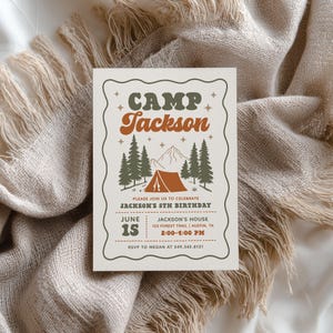 May include: A rectangular invitation card with a wavy border featuring the text CAMP JACKSON in green and orange. The design includes a mountain, pine trees, and a tent graphic. Details include Jackson's 5th birthday, June 15, 2:00-4:00 PM, 123 Forest Trail, Austin, TX, and RSVP to Megan at 549.345.8121.