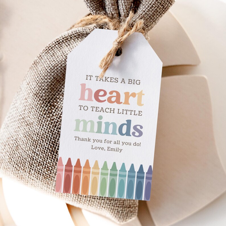 May include: A gift tag with the text "IT TAKES A BIG heart TO TEACH LITTLE minds" and a row of colorful crayons at the bottom. The tag says "Thank you for all you do! Love, Emily".