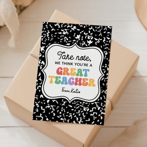 May include: A gift box with a greeting card that says "Take note, we think you're a GREAT TEACHER" in colorful letters. The card has a black and white notebook paper design and is signed "From Katie".