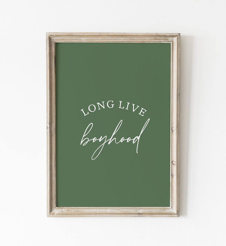 May include: Framed wall art with a green background and the words "LONG LIVE boyhood" in white script. The frame is a light, neutral color, and the artwork is displayed against a white wall.