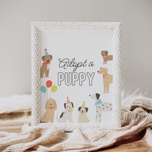 May include: A framed print with the words "Adopt a PUPPY" surrounded by cartoon dog illustrations. The dogs are in various poses and colors, some wearing party hats and collars. The frame is white with a textured, distressed finish.