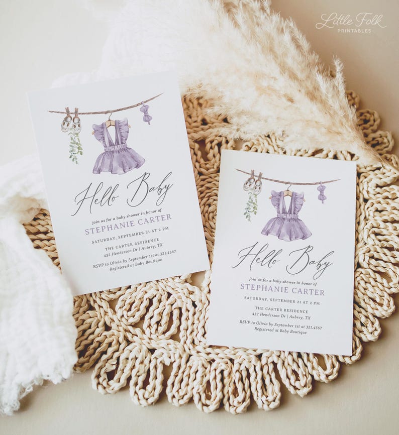 May include: Two baby shower invitations with a watercolor design. Each card features a purple dress hanging on a clothesline, with the words "Hello Baby" in elegant script. The invitations are on a white background.
