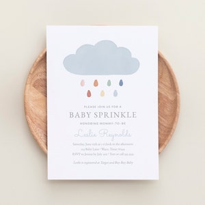 May include: A baby sprinkle invitation featuring a blue cloud and colourful raindrops. The invitation is for Leslie Reynolds and includes the date, time, location, and RSVP details.