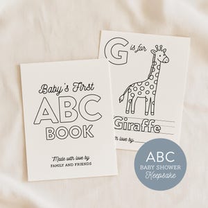 Puede incluir: Dos páginas de papel blanco de un libro de ABC para bebés. Una página presenta el texto Baby's First ABC BOOK y Made with love by FAMILY AND FRIENDS. La otra página muestra una letra G grande, una ilustración de jirafa y la palabra Giraffe.
