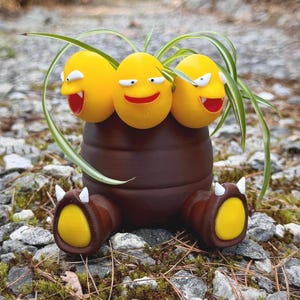 Peut inclure: Un pot marron fantaisiste avec trois visages jaunes souriants et des accents de plantes vertes. Le pot a deux pieds bruns avec des semelles jaunes et des griffes blanches. Un objet décoratif unique.