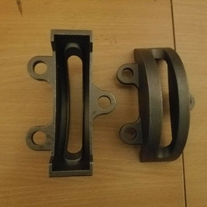 May include: Two black metal brackets with rounded edges and holes. The brackets have a slot cut out of the center.