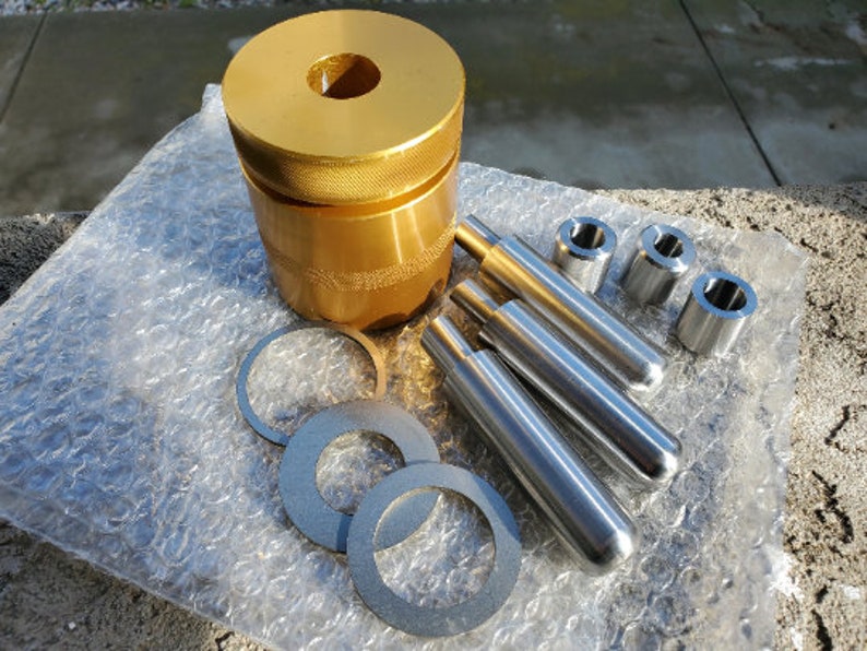 May include: A set of gold and silver metal tools for making jewelry. The set includes a gold cylinder with a hole in the center, three silver rods, and four silver rings.