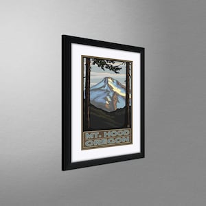 May include: A framed vintage travel poster featuring a stylized illustration of Mount Hood, Oregon. The poster is in a black frame and has a blue, white, and brown color scheme. The text "MT. HOOD OREGON" is printed at the bottom of the poster.