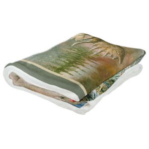 K&ouml;nnte beinhalten: Eine gefaltete Fleece-Decke mit einer Naturlandschaft mit einem Elch und B&auml;umen. Die Decke hat einen gr&uuml;nen Rand und eine wei&szlig;e R&uuml;ckseite.