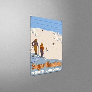 May include: Vintage-style metal sign featuring a ski scene at Sugar Mountain, North Carolina. The artwork depicts skiers on a snowy slope with a blue sky background. The sign includes the words "Ski Sugar Mountain North Carolina."