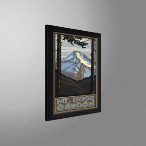 May include: A framed vintage travel poster featuring a stylized illustration of Mount Hood, Oregon. The poster is in a black frame and has a blue, white, and brown color scheme. The text "MT. HOOD OREGON" is printed at the bottom of the poster.