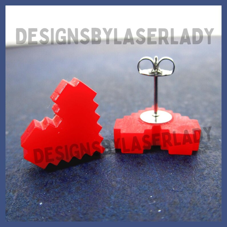 Puede incluir: Pendientes de bot&oacute;n de coraz&oacute;n pixelado rojo. Los pendientes son de material rojo con base negra. El texto "DESIGNSBYLASERLADY" es visible en la imagen. Los pendientes tienen un poste plateado.