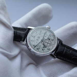 May include: A silver wristwatch with a white face and black leather band. The face features a unique design with Chinese characters and a depiction of a cityscape.