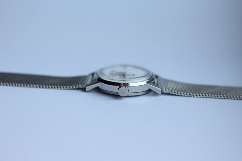 May include: A silver wristwatch with a white face and a silver mesh band.