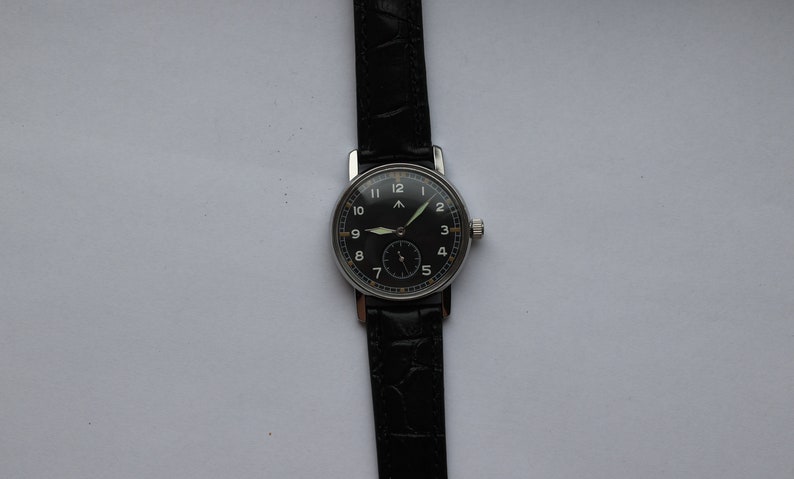 May include: A black-faced wristwatch with white numerals and a black leather band. The watch has a silver case and a small second hand.
