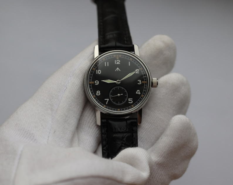 May include: A black-faced wristwatch with white numerals and a black leather strap. The watch has a silver case and a silver second hand.