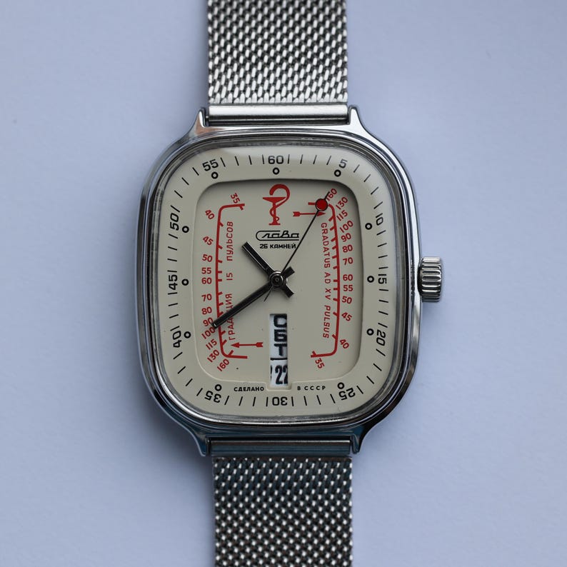 May include: Vintage silver-toned wristwatch with a mesh band. The watch face is off-white with red and black markings, including a pulse scale and the text "Слава". The date is displayed at the bottom.