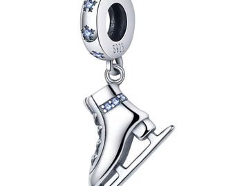 May include: A silver charm with a figure skate pendant. The charm features a round top with snowflake accents and the text "S925". The skate has blue gemstone accents.