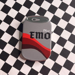 May include: A gray Diet EMO can-shaped object with red and dark red wavy stripes. The text "Diet EMO" is printed on the front in a gothic font. The background is a black and white checkered pattern.